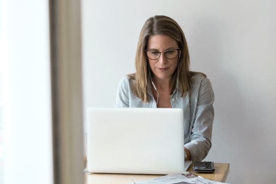 Una persona guarda concentratamente il suo laptop mentre sta elaborando una richiesta di cliente.